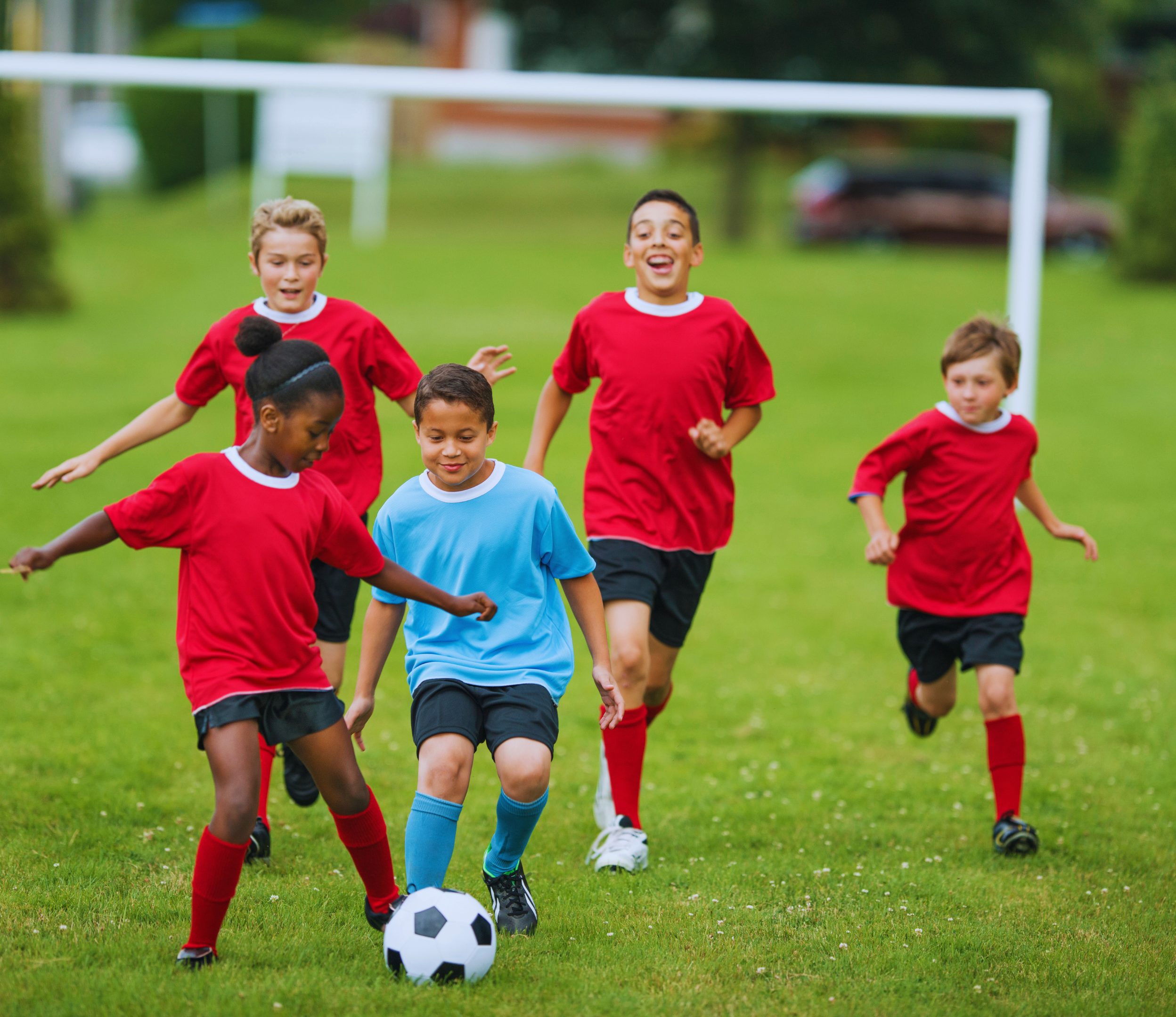 Kids playing soccer in a field.