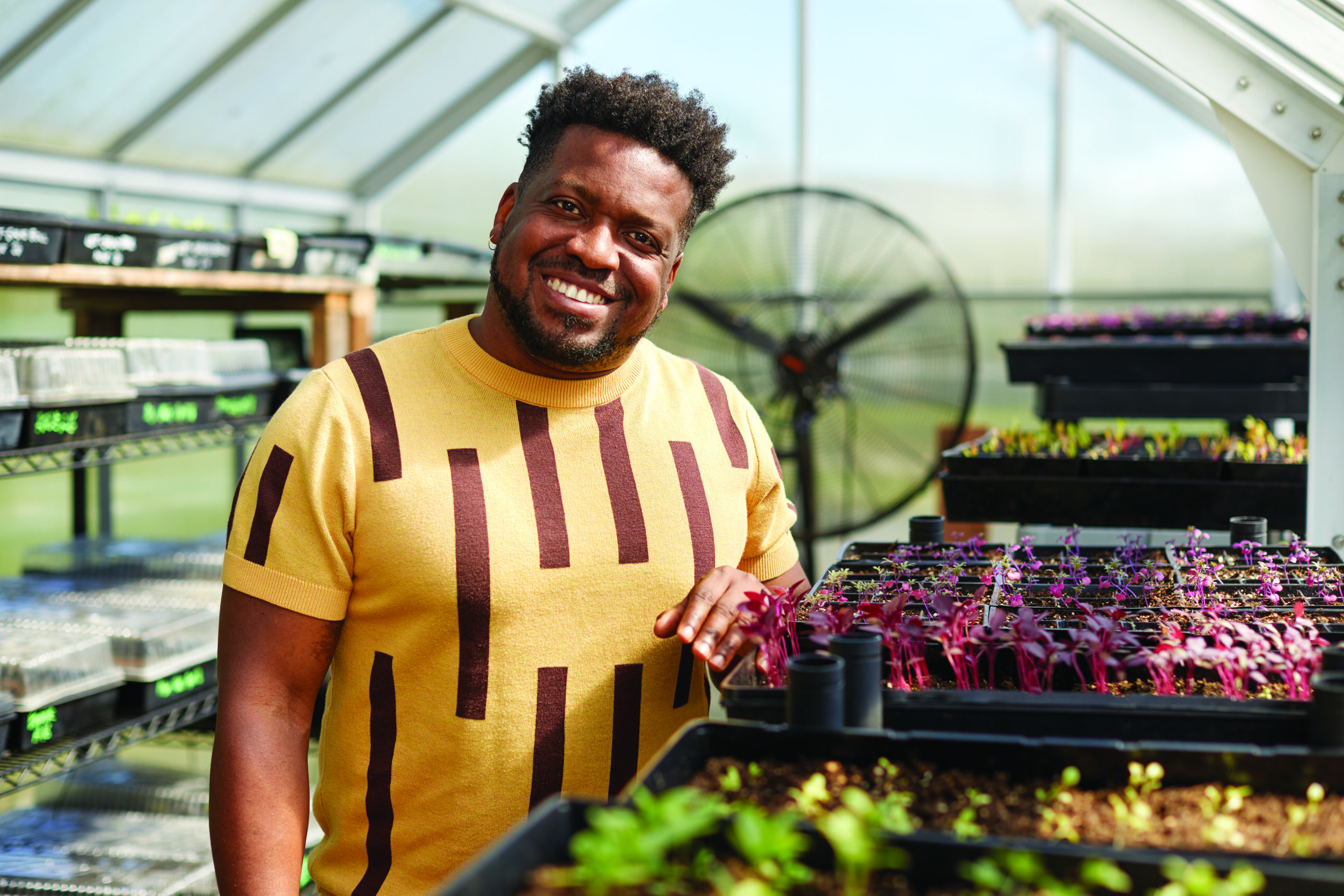 Ariel of Iye Creative standing next to plants in greenhouse.