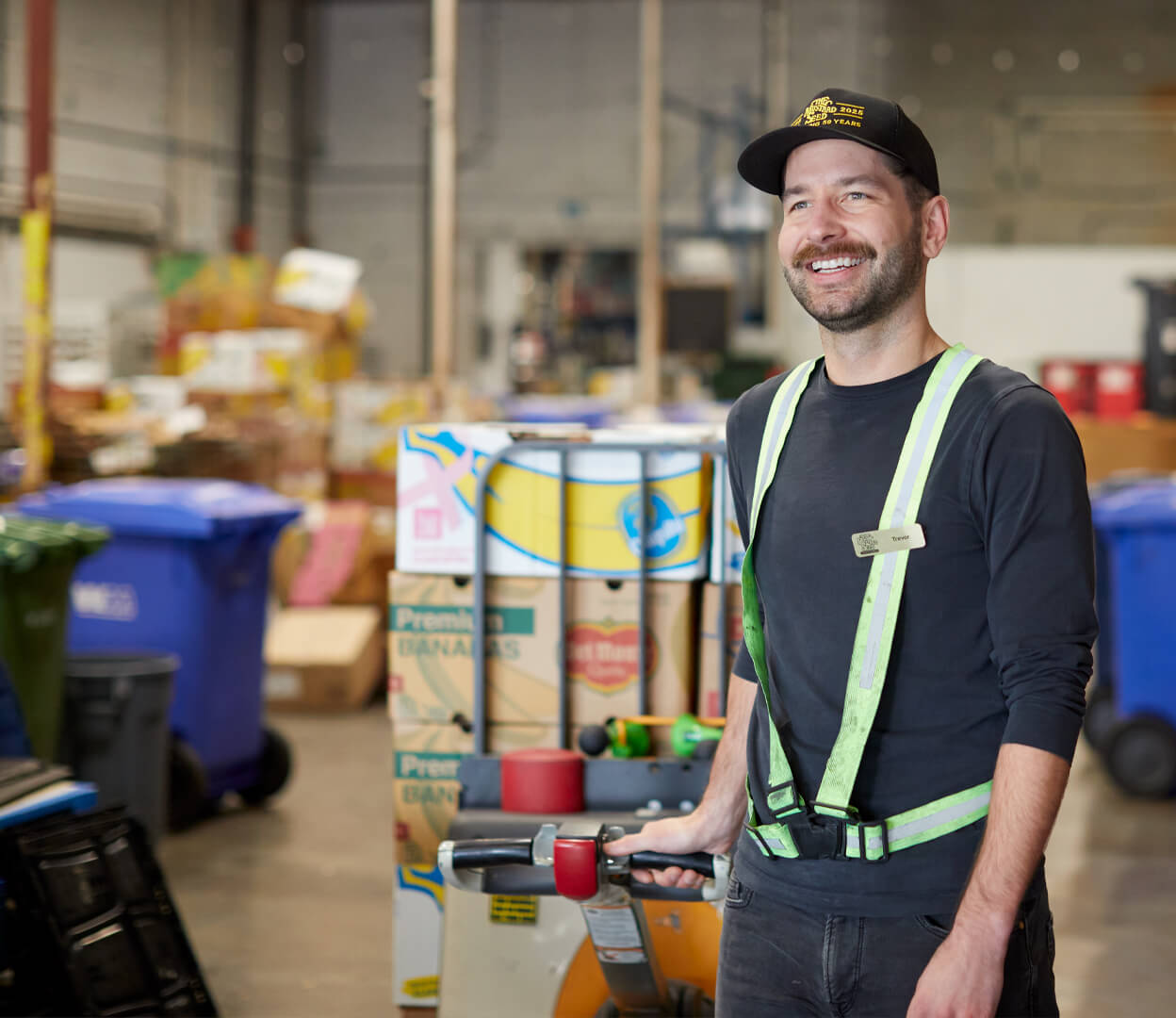 A smiling man moves a palette loaded with rescued food at the Mustard Seed Food Security Distribution Centre.