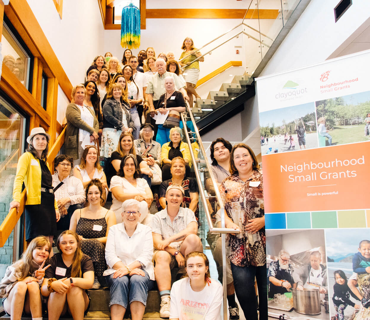 A group of people associated with the Neighbourhood Small Grants Program gather on a large staircase for a group portrait.