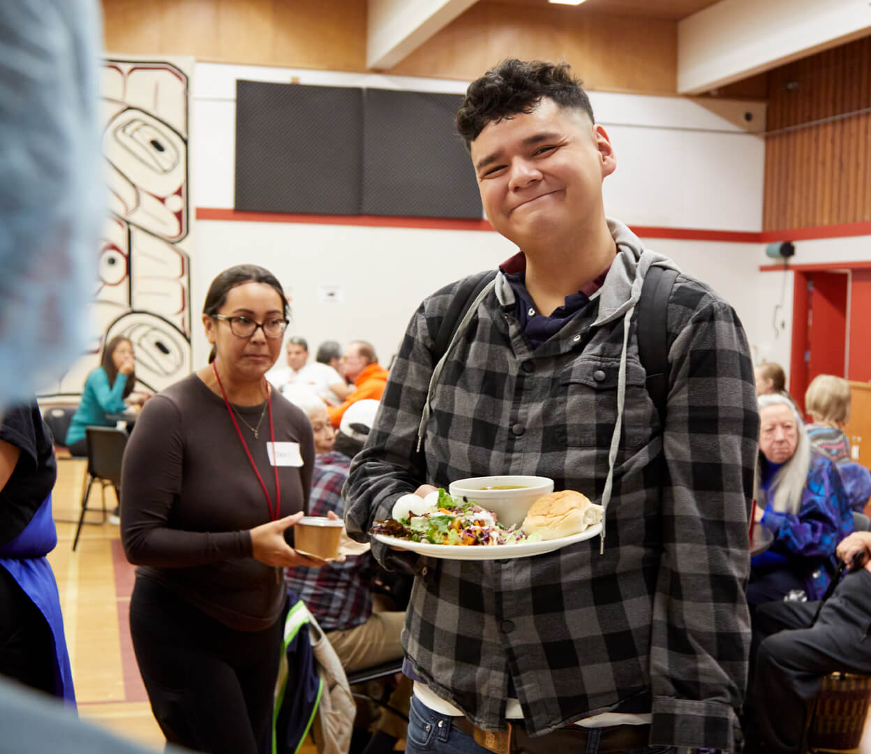 A smiling young person looks at the camera while enjoying lunch at the Victoria Native Friendship Centre.