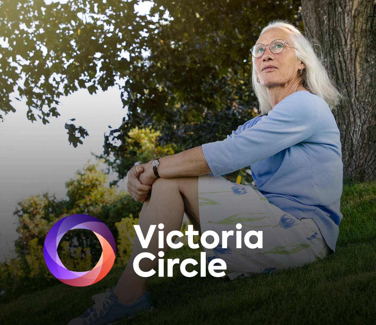 A woman is sitting on a grassy hill looking thoughtful. The Victoria Circle logo appears overtop of the image.