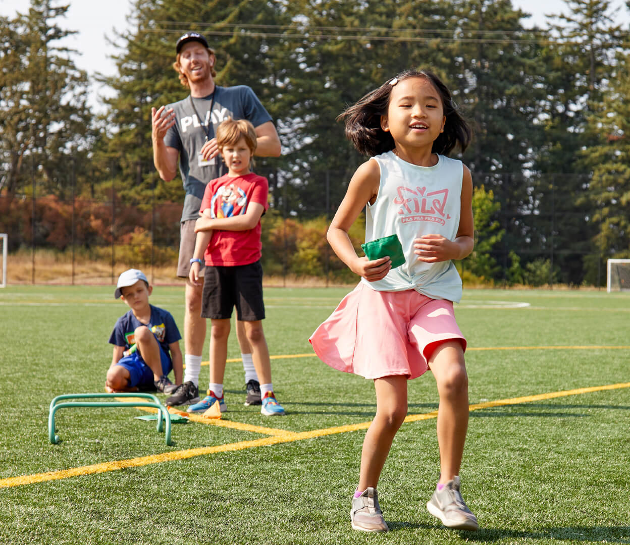Children play a game outside with a leader from the Pacific Institute for Sport Education.
